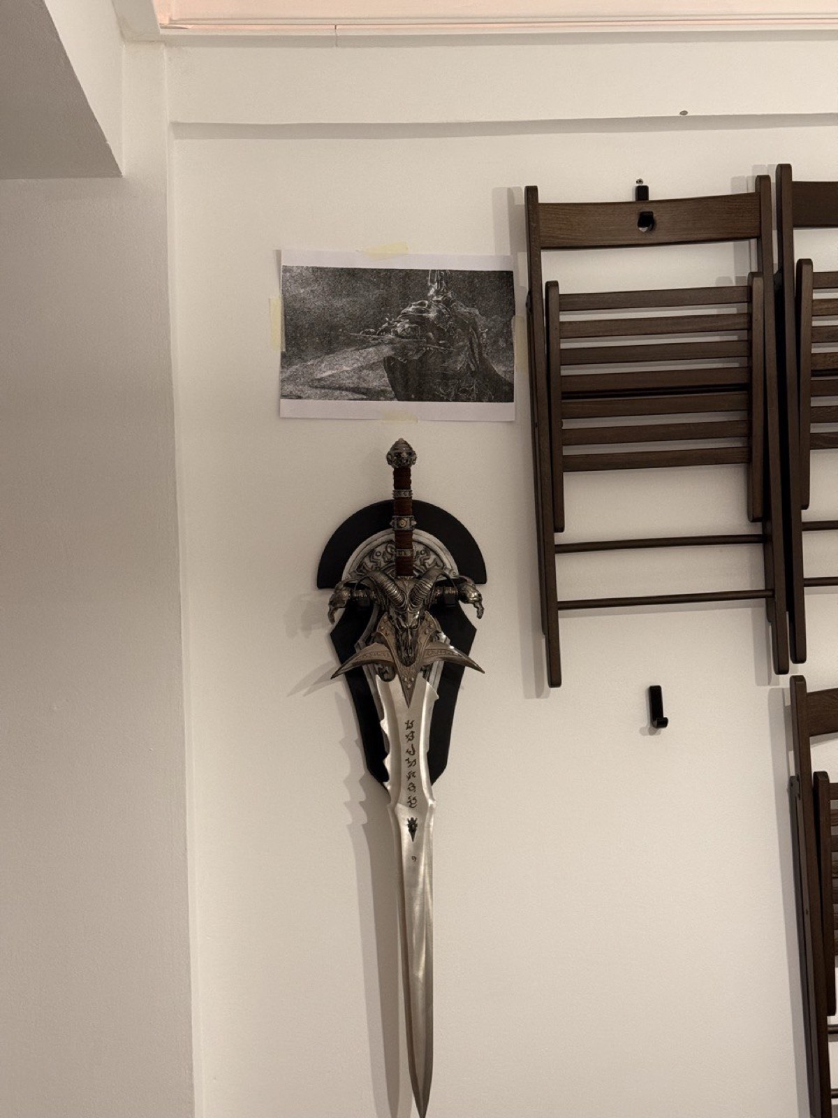 Cross-hatched print hung on a wall next to a replica sword.