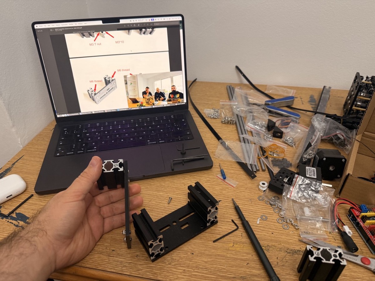 Building the first plotter: parts spread on a desk with assembly instructions on the laptop screen.