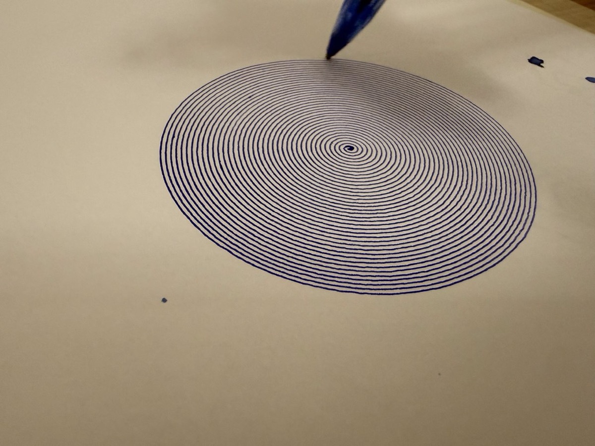 A tight spiral being drawn by the plotter, pen tip visible.