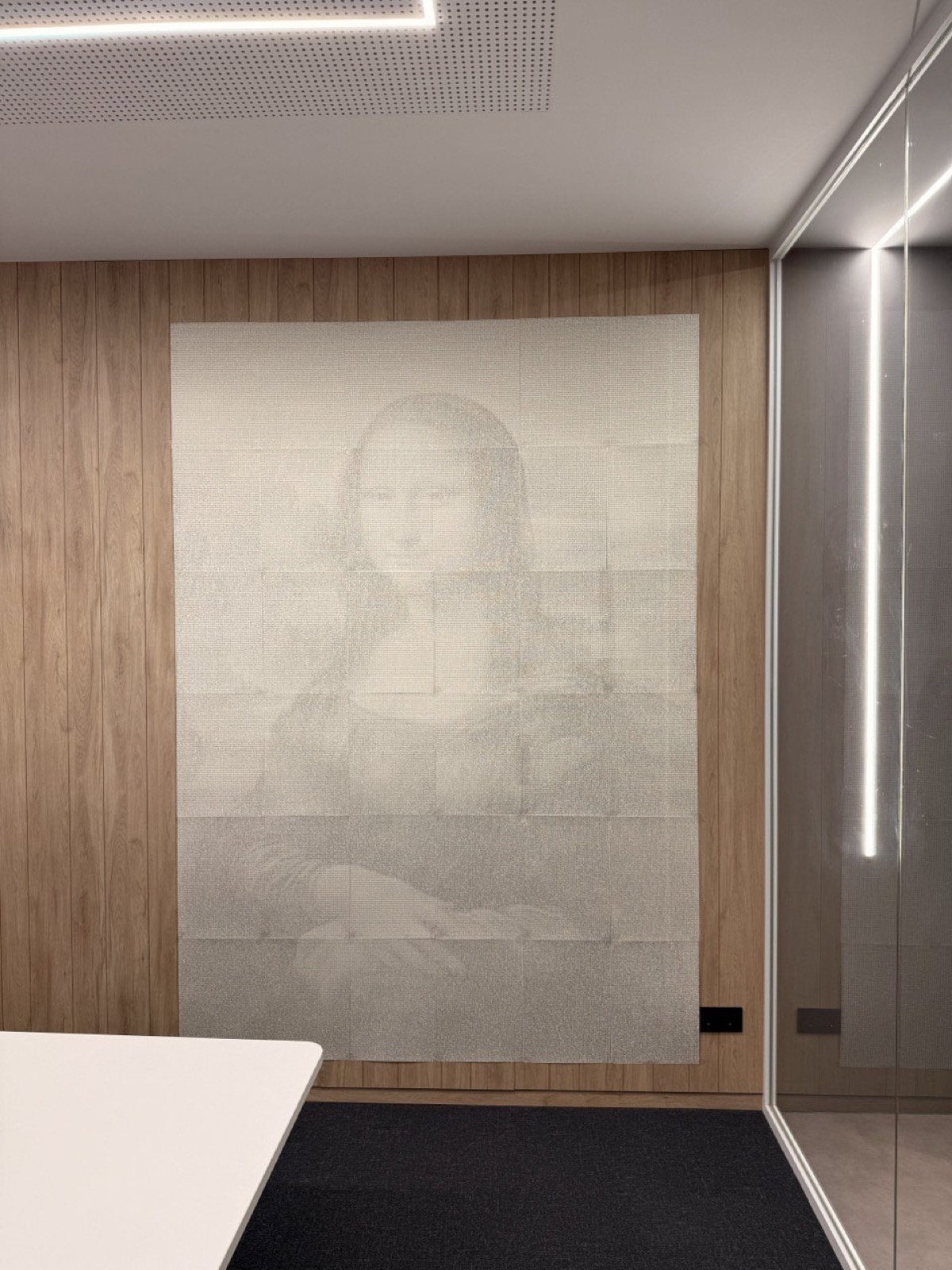 The complete 1.78 by 2.52 meter Mona Lisa mosaic mounted on an office wall, recognizable from across the room.
